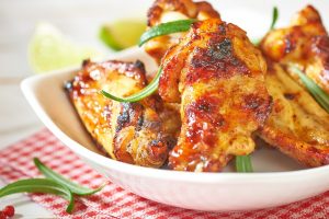 Teriyaki chicken wings. Baked chicken  with fresh rosemary. Homemade food. Symbolic image. Concept for a tasty and healty dish. Bright wooden background. Close up.